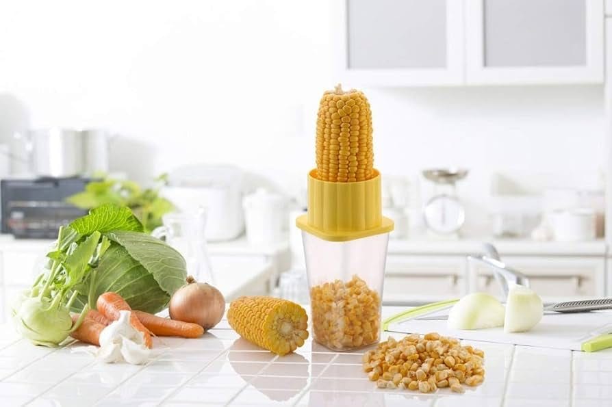 A corn kernel remover tool extracting kernels from a corn cob into a transparent container. This kitchen gadget efficiently separates corn kernels for easy food preparation.