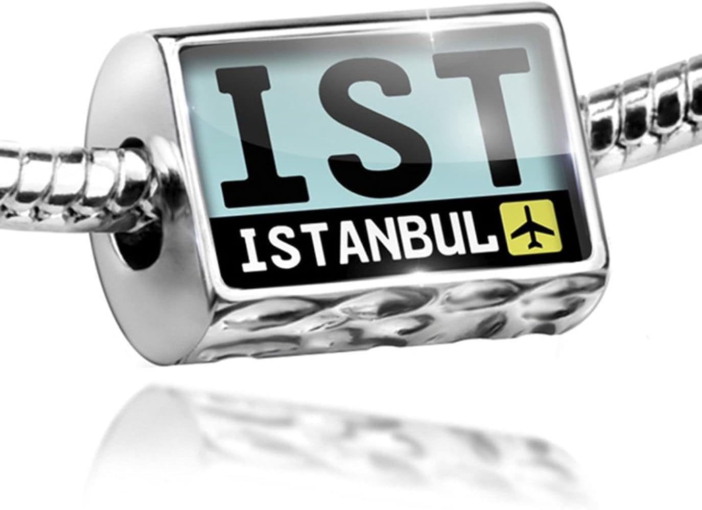 A silver charm bead featuring the airport code "IST" for Istanbul, with a light blue background, bold black letters, and a small airplane icon