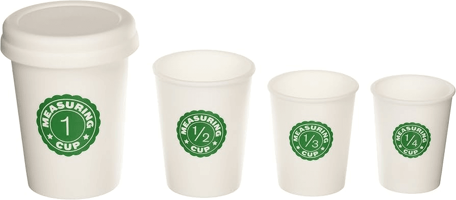 A set of four white measuring cups with green labels indicating their capacities: 1 cup, 1/2 cup, 1/3 cup, and 1/4 cup. The largest cup has a lid, and each cup has a simple, clean design